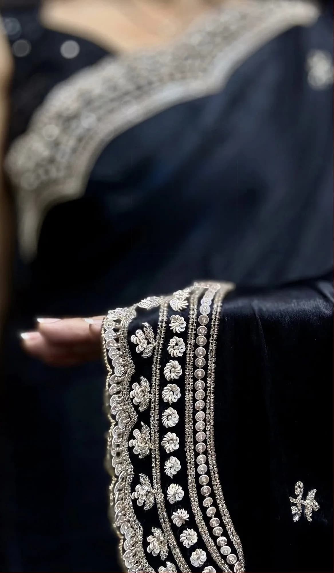 Close-up of silver embroidery on the border of a black saree
